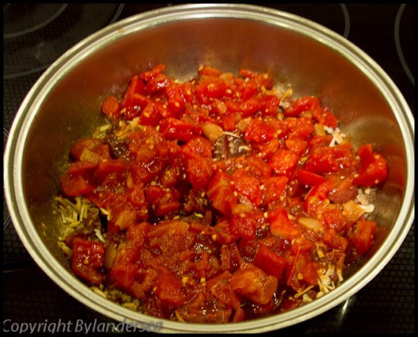 Add the tomatoes to the skillet. Pour a can of tomatoes on top.