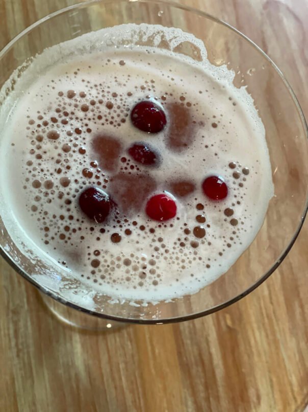 Cranberries float on top of the frothy cocktail.